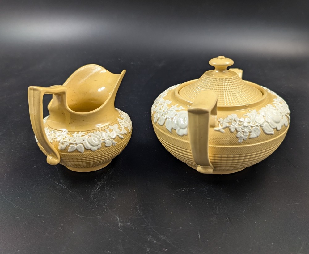 A Regency period buff stoneware teapot and matching creamer jug featuring engine-turned lattice patterning and applied white botanical reliefs. View III