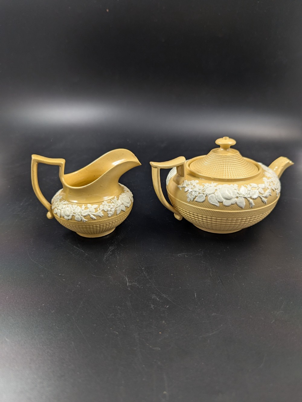 A Regency period buff stoneware teapot and matching creamer jug featuring engine-turned lattice patterning and applied white botanical reliefs. View V