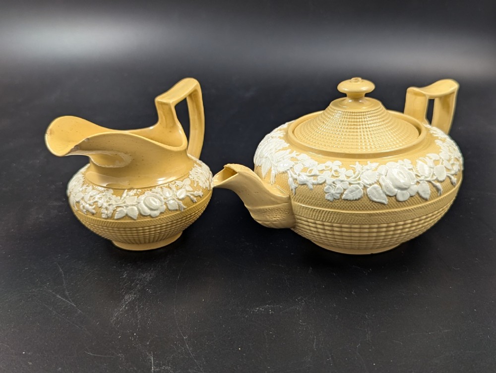 A Regency period buff stoneware teapot and matching creamer jug featuring engine-turned lattice patterning and applied white botanical reliefs. View VI
