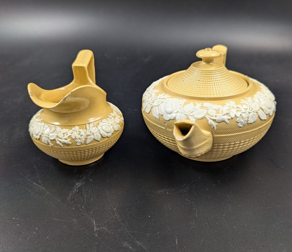 A Regency period buff stoneware teapot and matching creamer jug featuring engine-turned lattice patterning and applied white botanical reliefs. View VII