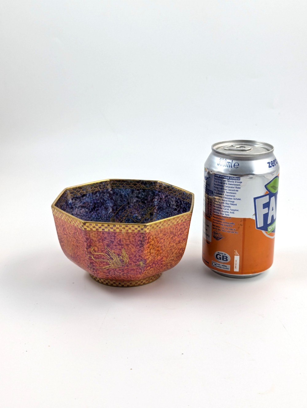 An octagonal Art Deco porcelain bowl featuring a mottled pink exterior with gold mythological motifs and an iridescent blue interior bounded by a gilded checkered rim. View V