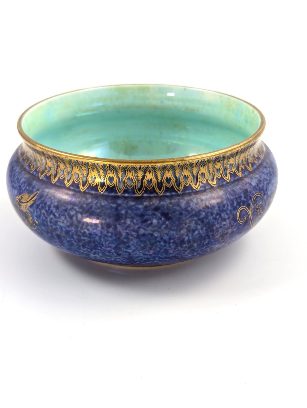A rounded ceramic bowl featuring a mottled blue exterior decorated with a gilded dragon motif, a gilt patterned rim, and a pale iridescent green interior glaze. View IV