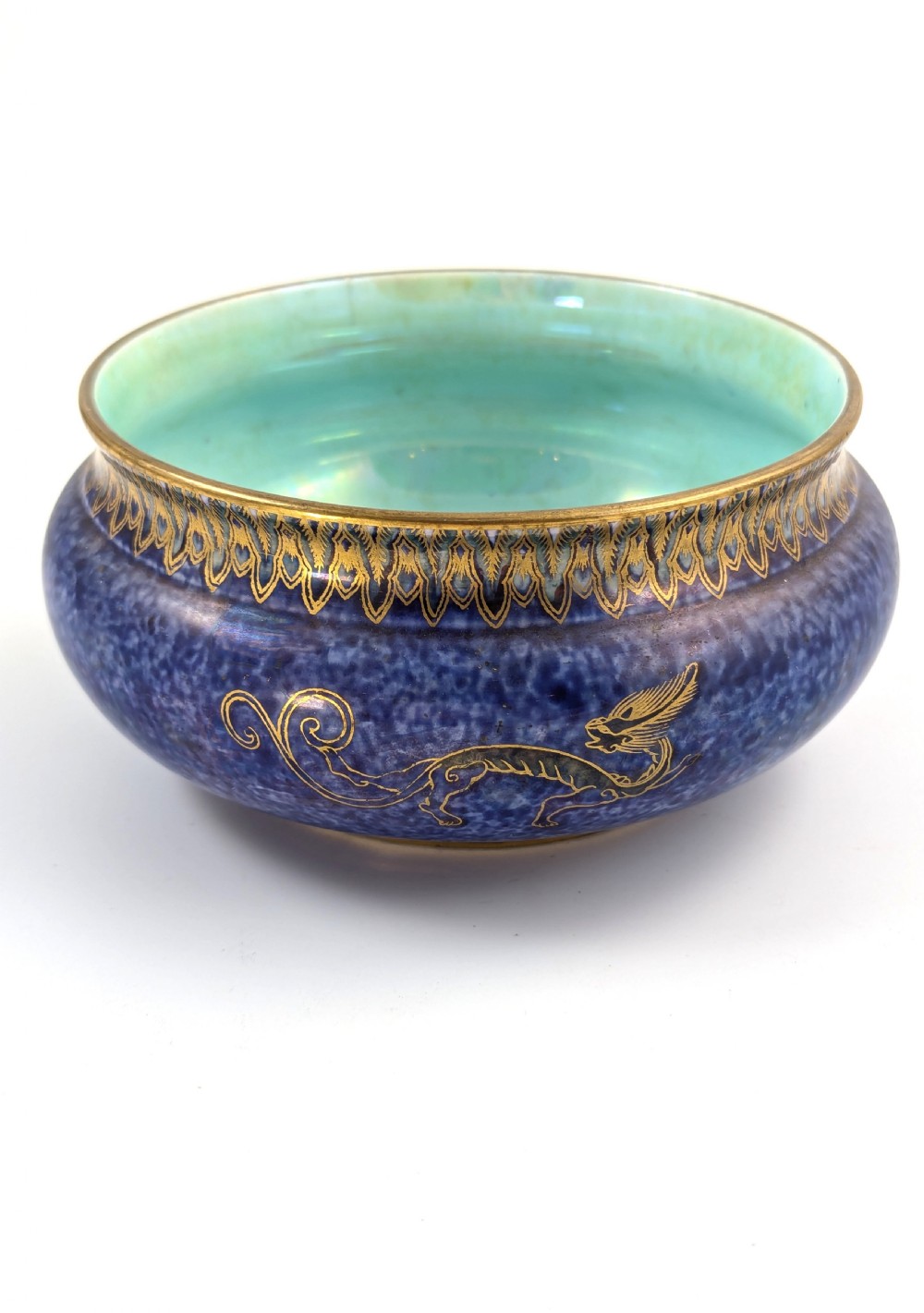 A rounded ceramic bowl featuring a mottled blue exterior decorated with a gilded dragon motif, a gilt patterned rim, and a pale iridescent green interior glaze. View V