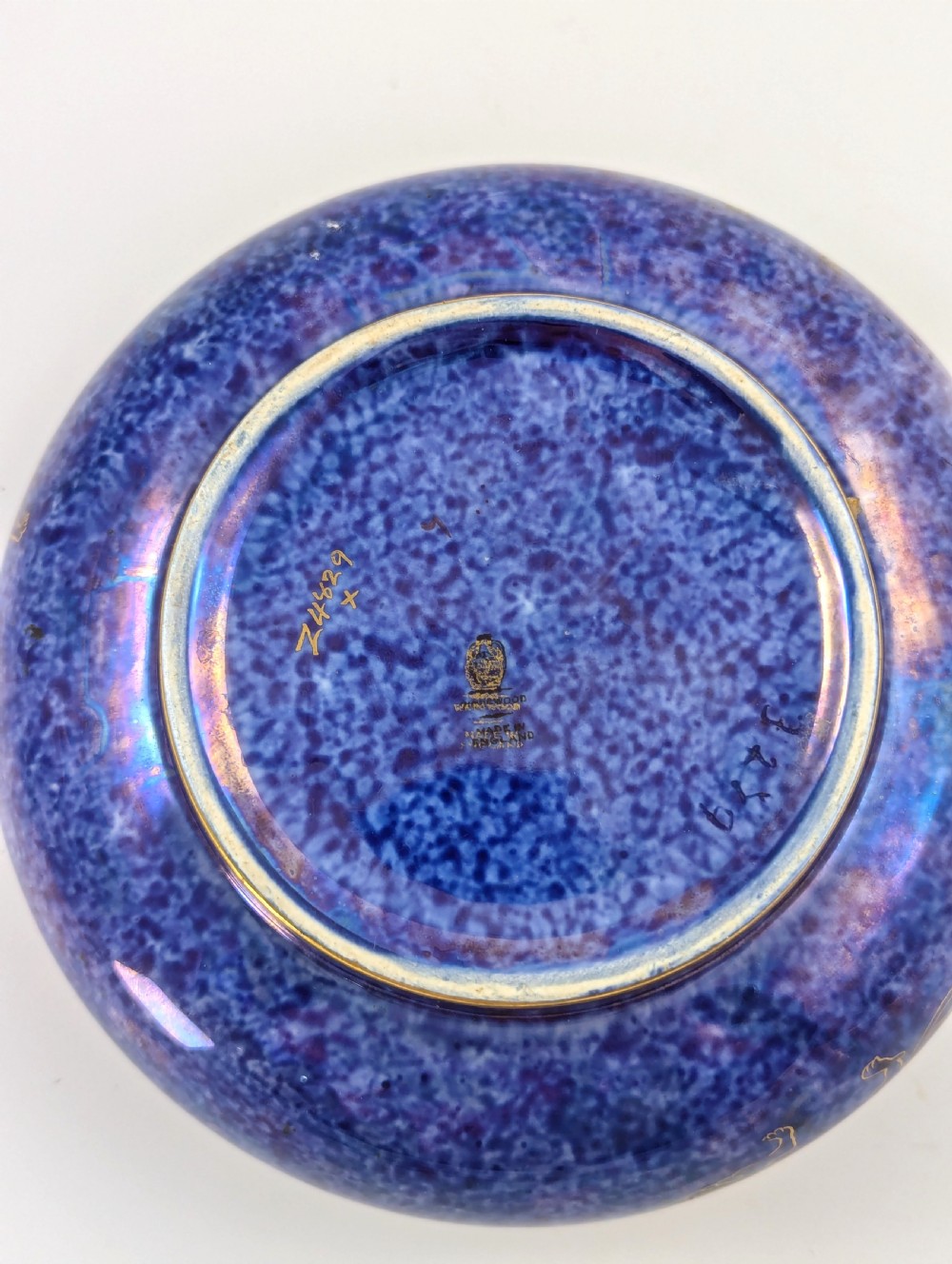 A rounded ceramic bowl featuring a mottled blue exterior decorated with a gilded dragon motif, a gilt patterned rim, and a pale iridescent green interior glaze. View VI