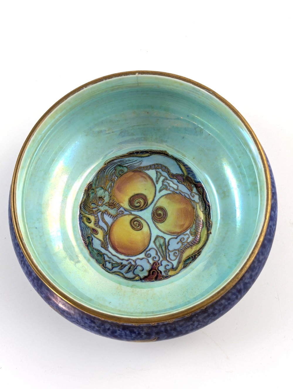 A rounded ceramic bowl featuring a mottled blue exterior decorated with a gilded dragon motif, a gilt patterned rim, and a pale iridescent green interior glaze. View VII