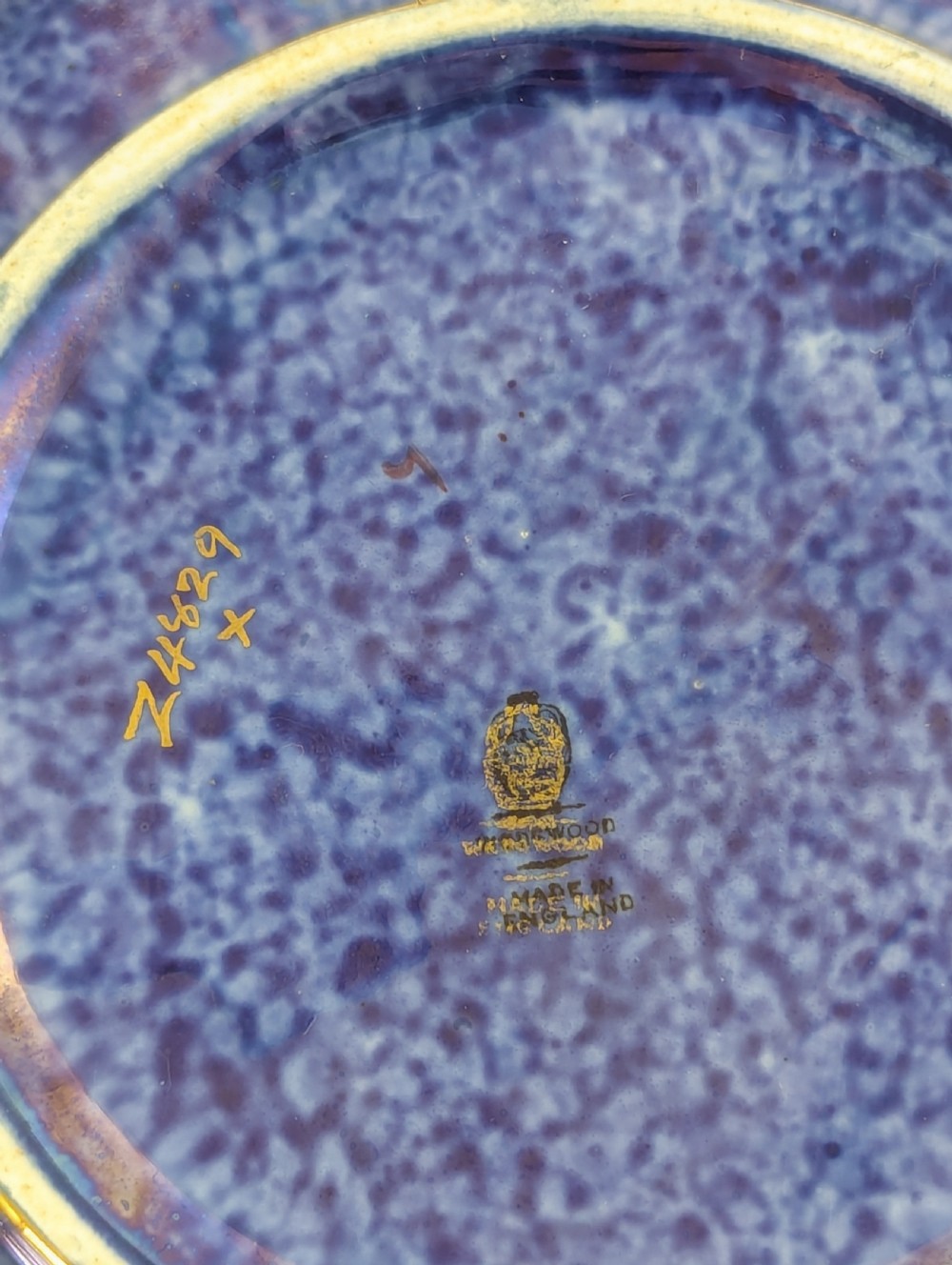 A rounded ceramic bowl featuring a mottled blue exterior decorated with a gilded dragon motif, a gilt patterned rim, and a pale iridescent green interior glaze. View IX