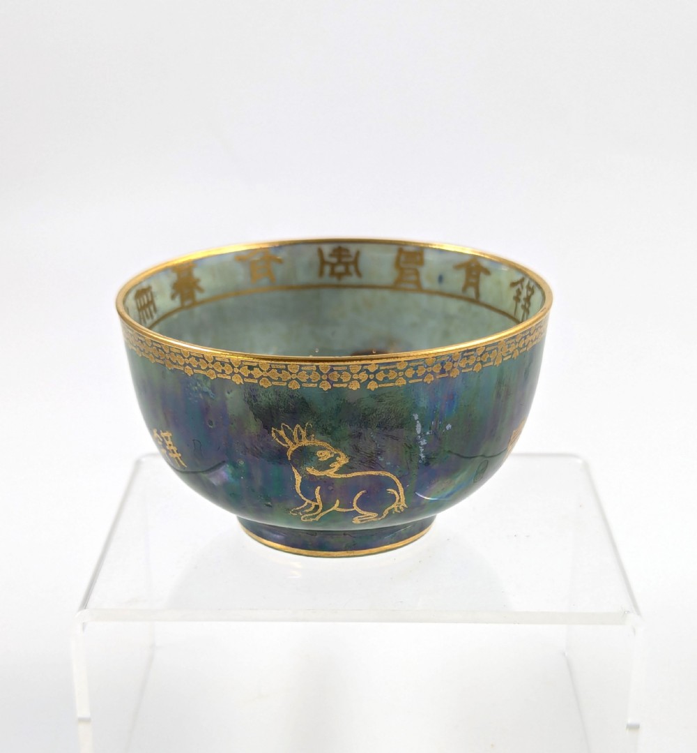 An Art Deco Wedgwood lustre bowl featuring an iridescent green glaze and gilded depictions of mythic animals and Chinese characters.