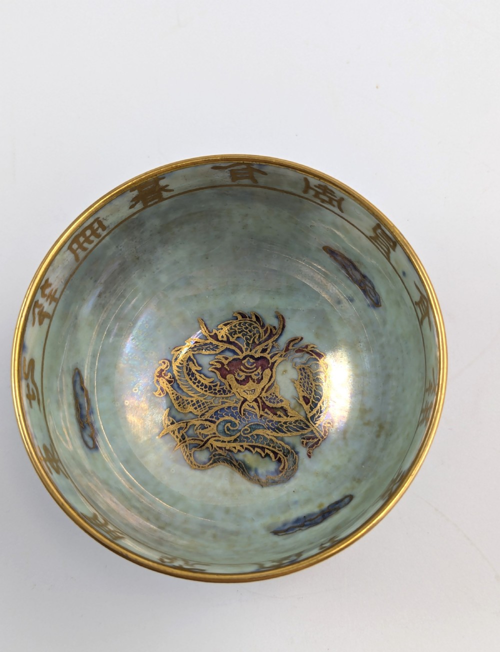An Art Deco Wedgwood lustre bowl featuring an iridescent green glaze and gilded depictions of mythic animals and Chinese characters. View VI