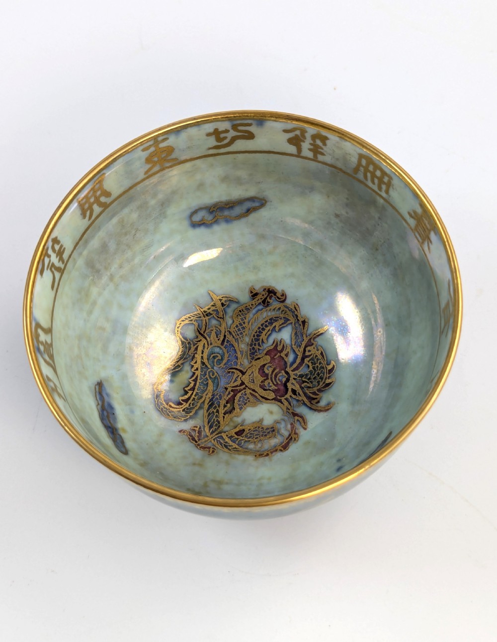An Art Deco Wedgwood lustre bowl featuring an iridescent green glaze and gilded depictions of mythic animals and Chinese characters. View VIII