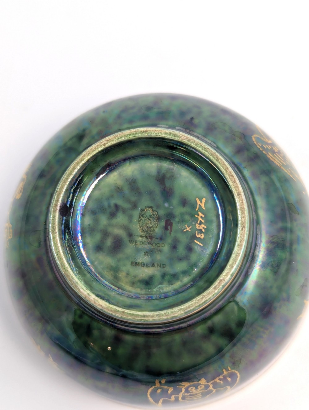 An Art Deco Wedgwood lustre bowl featuring an iridescent green glaze and gilded depictions of mythic animals and Chinese characters. View IX