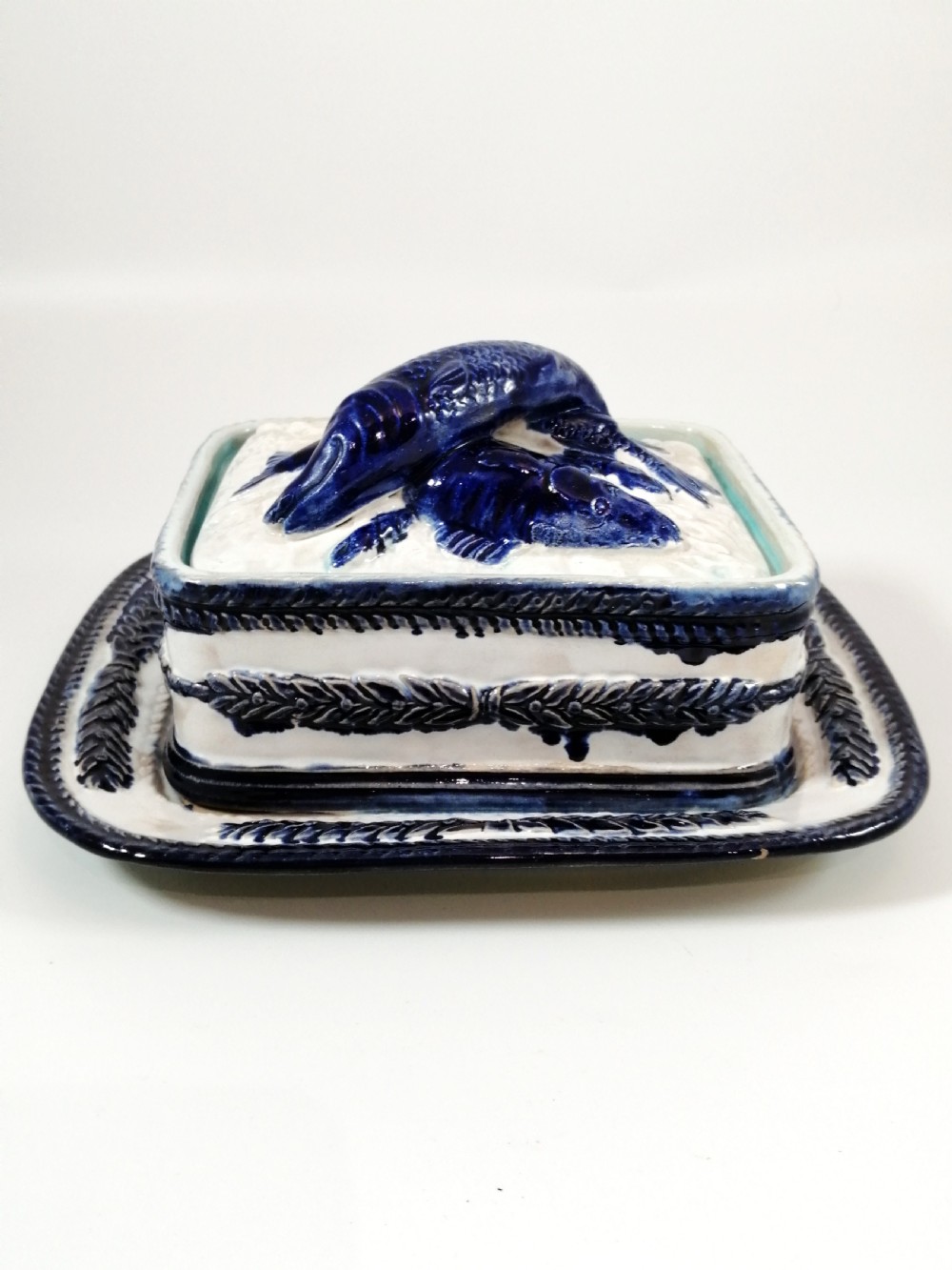 A rectangular Victorian majolica sardine box with matching undertray featuring cobalt blue fish relief decoration on an off-white lid. View III