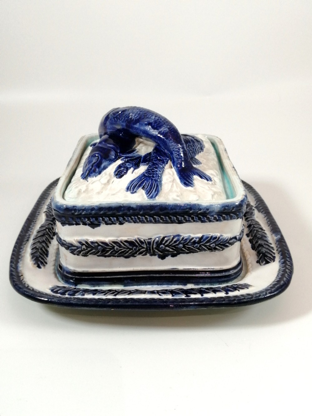 A rectangular Victorian majolica sardine box with matching undertray featuring cobalt blue fish relief decoration on an off-white lid. View V