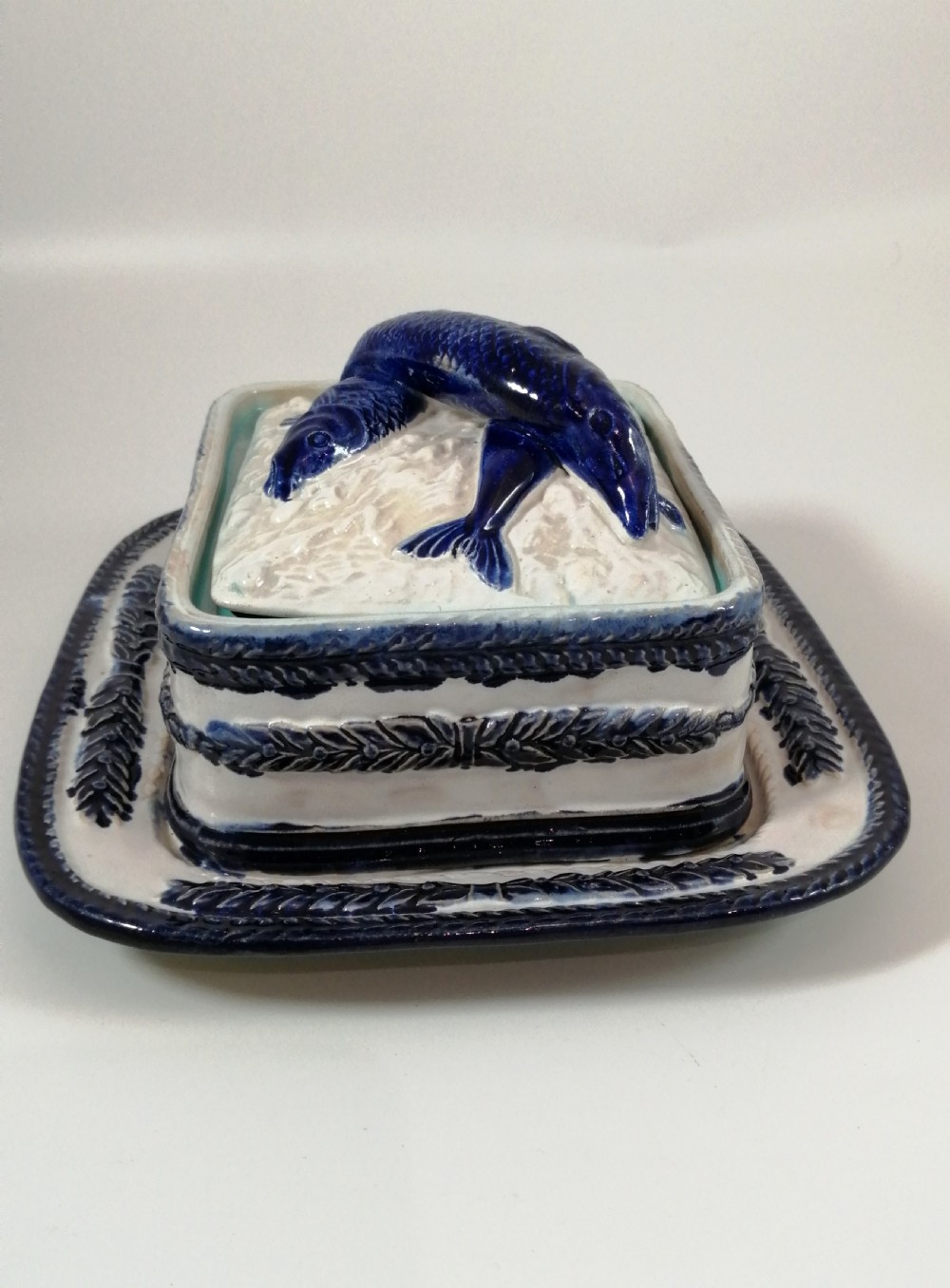 A rectangular Victorian majolica sardine box with matching undertray featuring cobalt blue fish relief decoration on an off-white lid. View IX