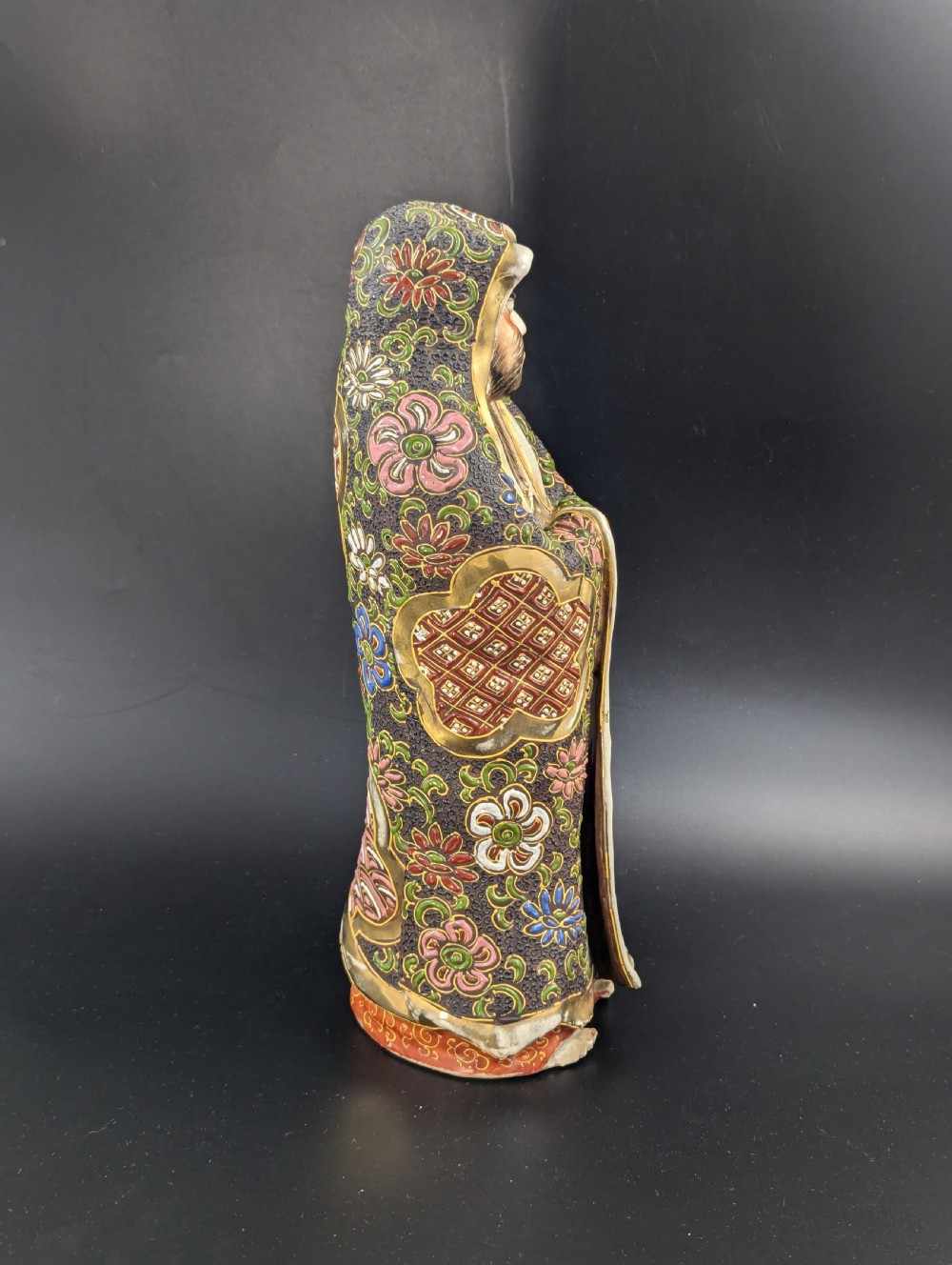 A Japanese Satsuma earthenware figurine depicting a bearded Daruma monk wearing a hooded robe with polychrome enamels and gold accents. View VIII