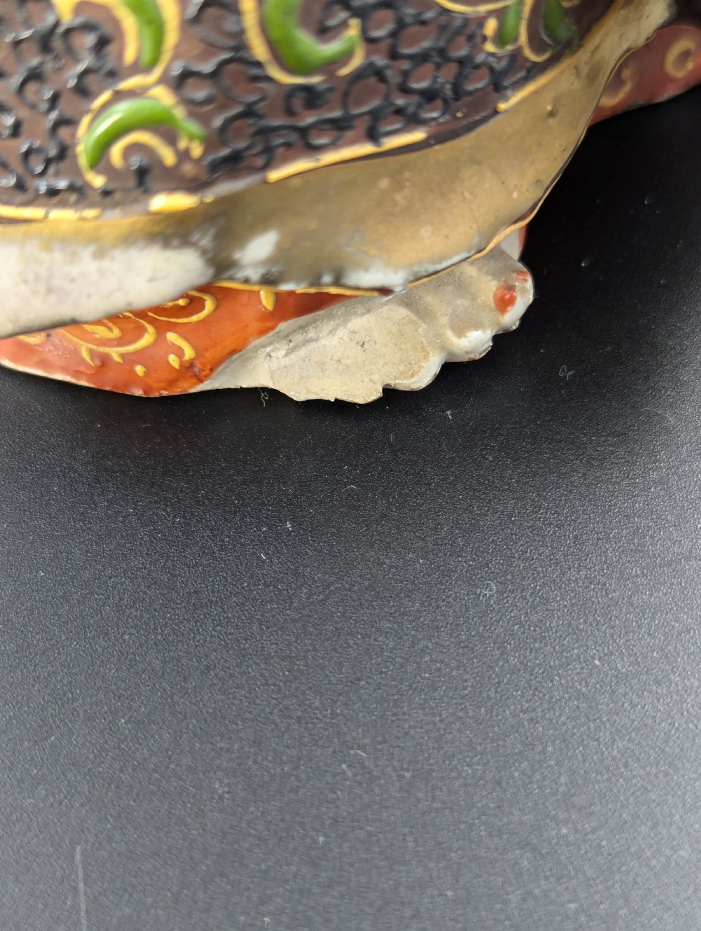 A Japanese Satsuma earthenware figurine depicting a bearded Daruma monk wearing a hooded robe with polychrome enamels and gold accents. View XI