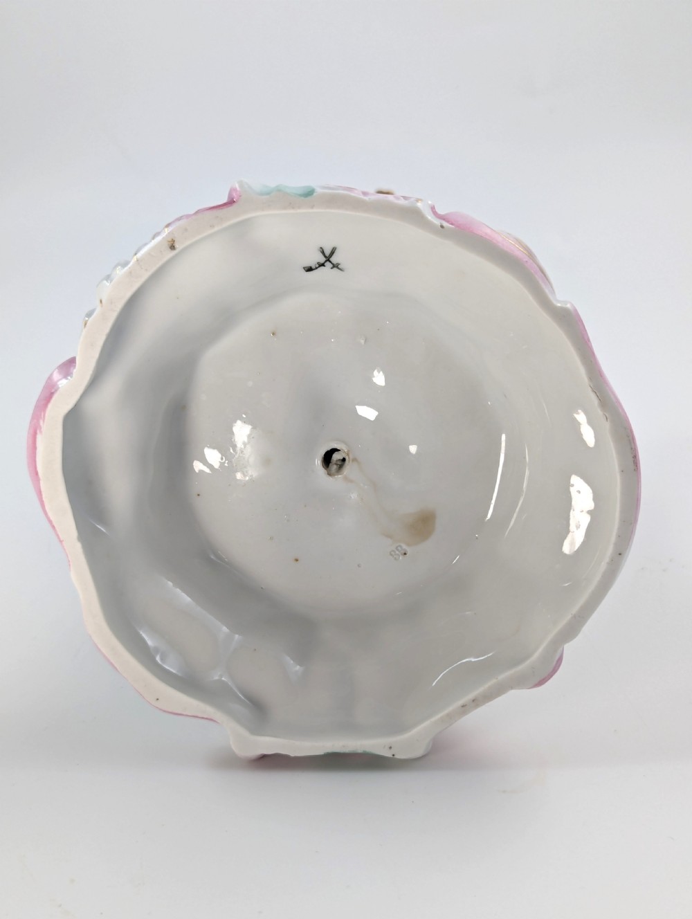 A 19th-century German hard-paste porcelain candlestick featuring two sculpted cherubs around a central column on a pastel Rococo scroll base. View IX