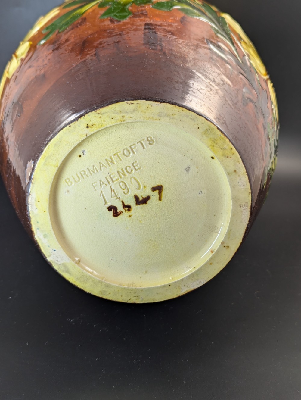 A tall ceramic vase featuring a yellow neck and upper body with raised impasto floral decoration transitioning into a dark brown glazed base. View IV