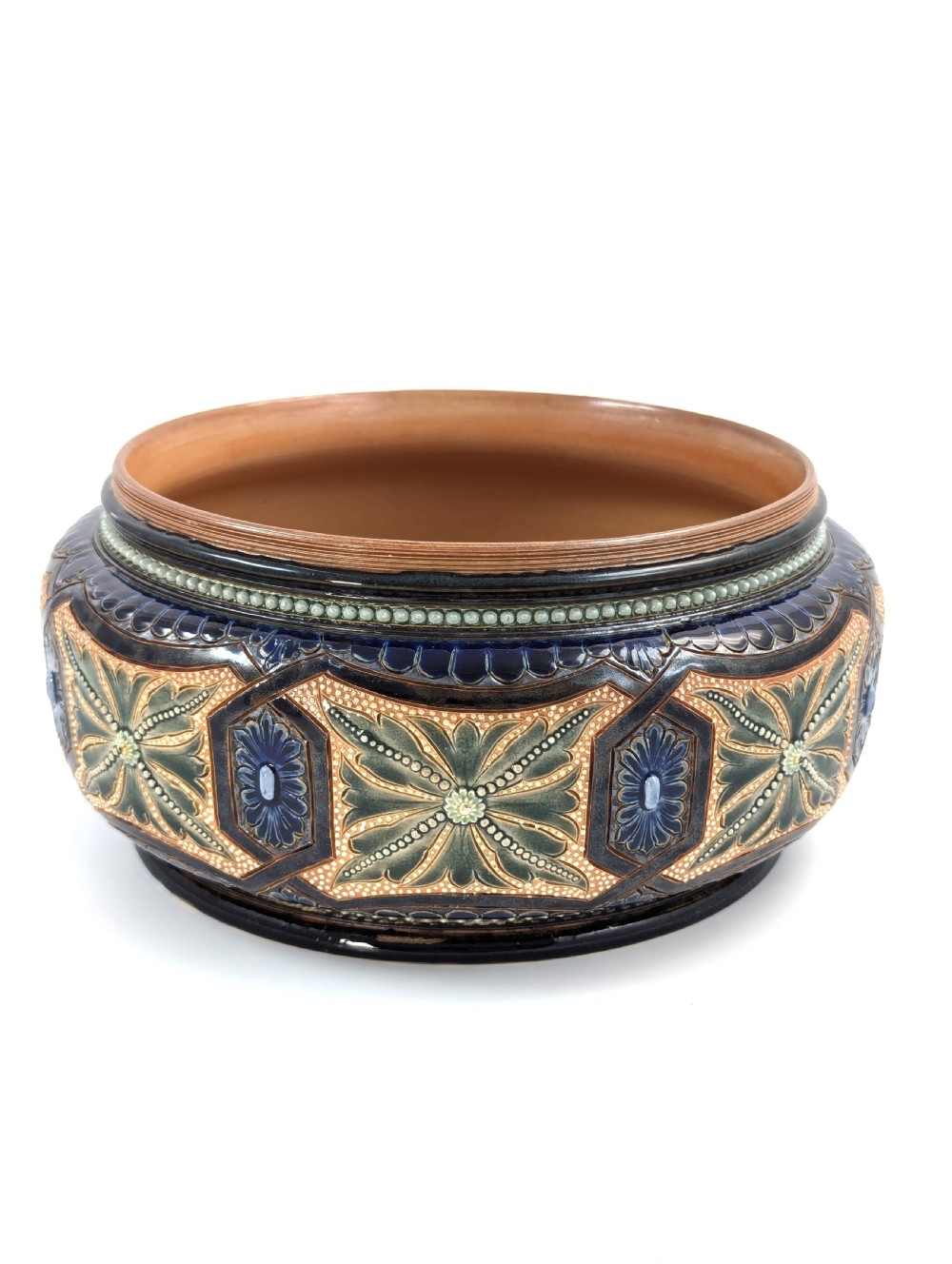 A Victorian Doulton Lambeth stoneware salad bowl decorated with cobalt blue and terracotta geometric patterns, presented with two matching ceramic-handled silver servers. View II