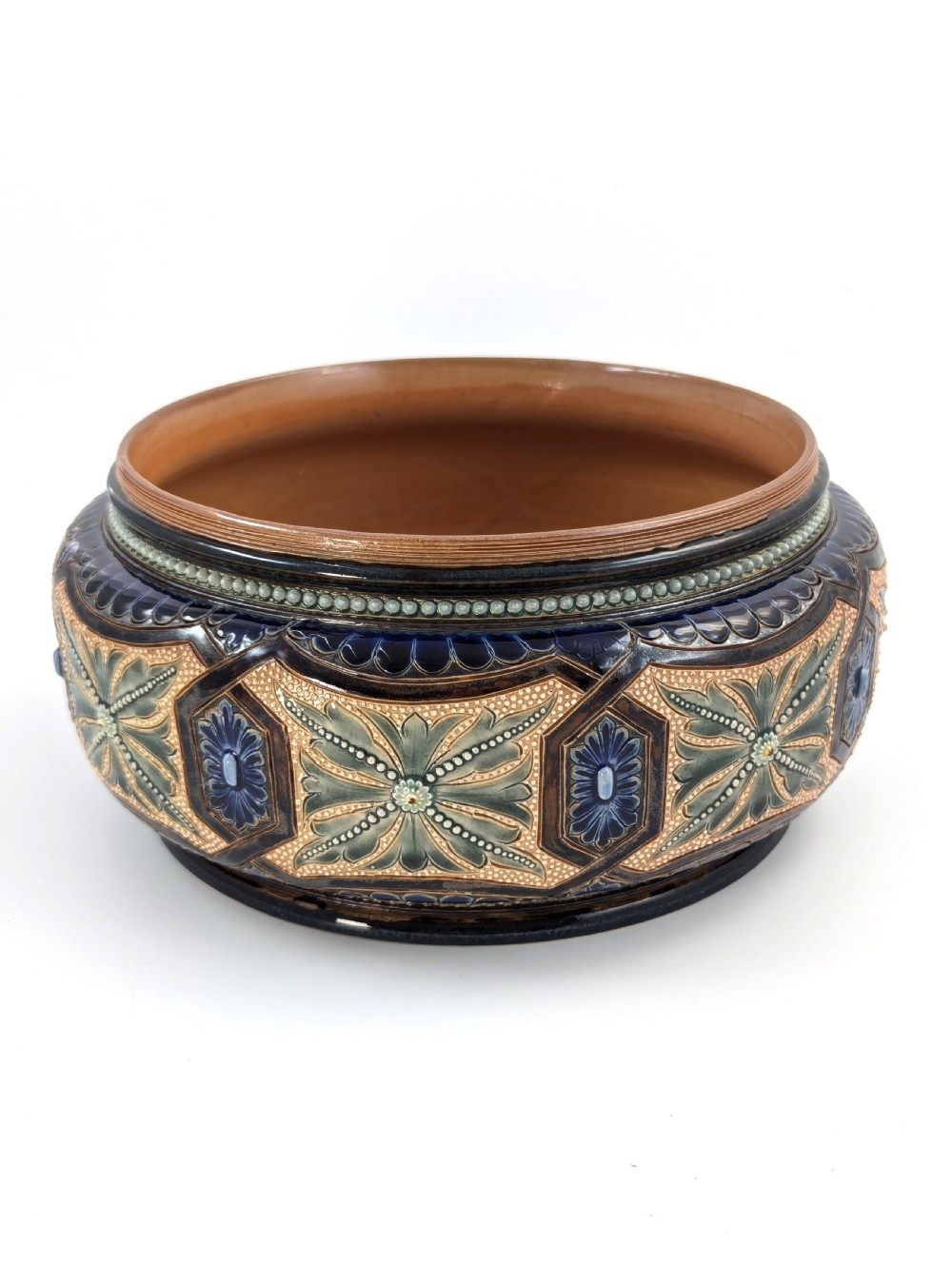 A Victorian Doulton Lambeth stoneware salad bowl decorated with cobalt blue and terracotta geometric patterns, presented with two matching ceramic-handled silver servers. View V