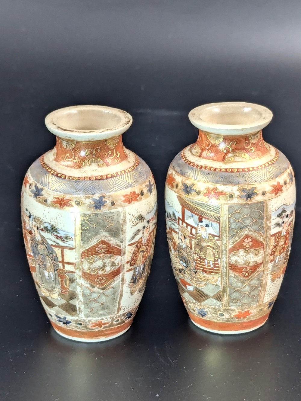 A pair of small Japanese Kutani porcelain vases featuring figurative narrative panels framed by iron-red and gold leaf borders. View II