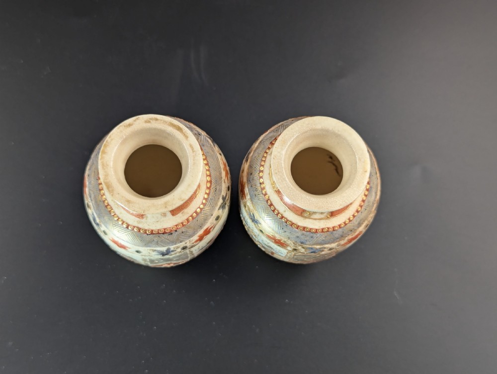 A pair of small Japanese Kutani porcelain vases featuring figurative narrative panels framed by iron-red and gold leaf borders. View V