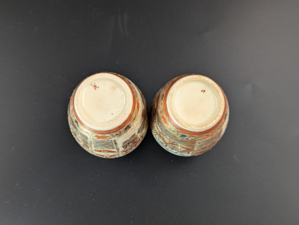 A pair of small Japanese Kutani porcelain vases featuring figurative narrative panels framed by iron-red and gold leaf borders. View VI