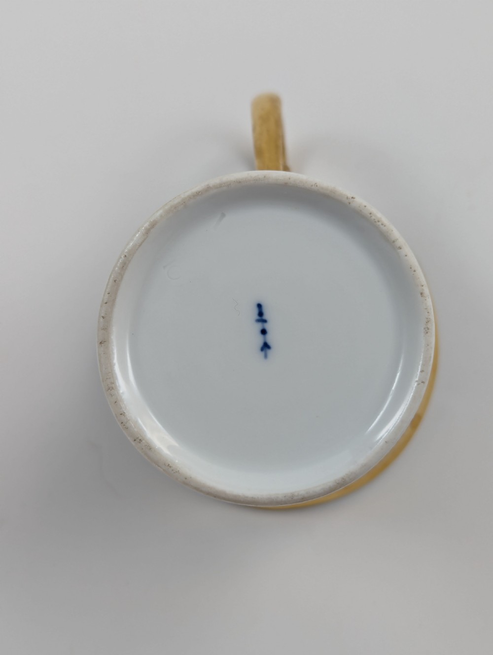 A Neoclassical KPM Berlin porcelain teacup and saucer featuring heavy gold leaf gilding, a maroon background with star patterns, and a high curved loop handle. View IX