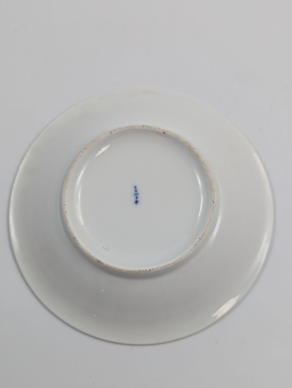 A Neoclassical KPM Berlin porcelain teacup and saucer featuring heavy gold leaf gilding, a maroon background with star patterns, and a high curved loop handle. View XI