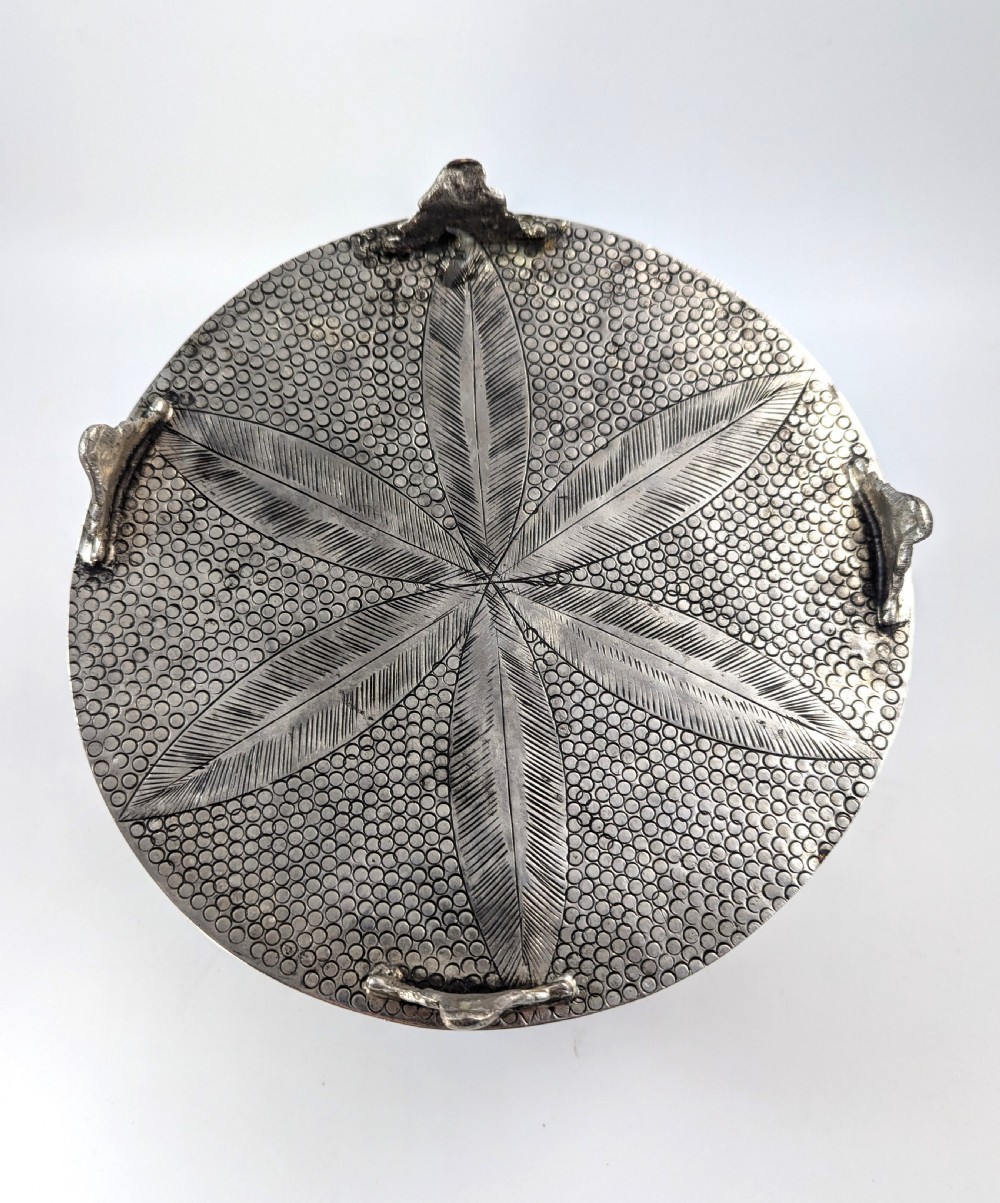 A circular silver-plated box decorated with intricate chased floral motifs and low-relief figures of Krishna and Radha on the lid. View VII