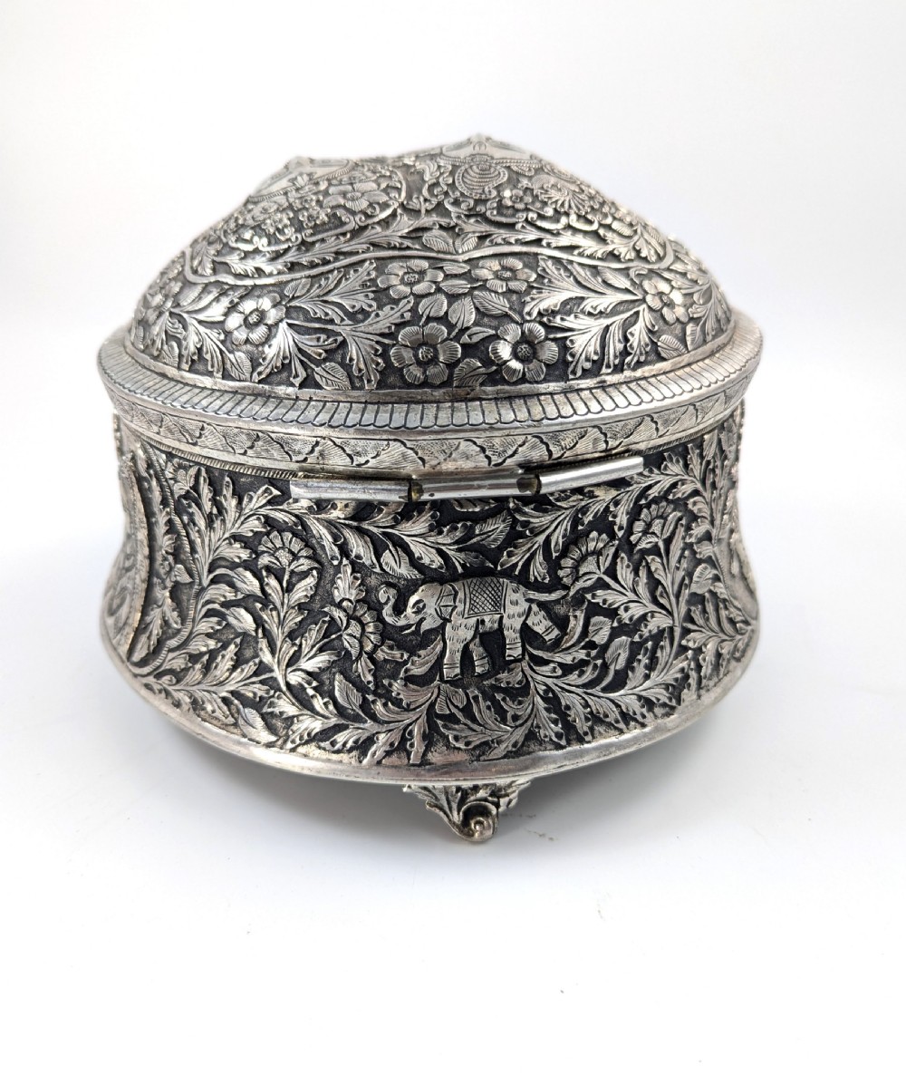 A circular silver-plated box decorated with intricate chased floral motifs and low-relief figures of Krishna and Radha on the lid. View IX