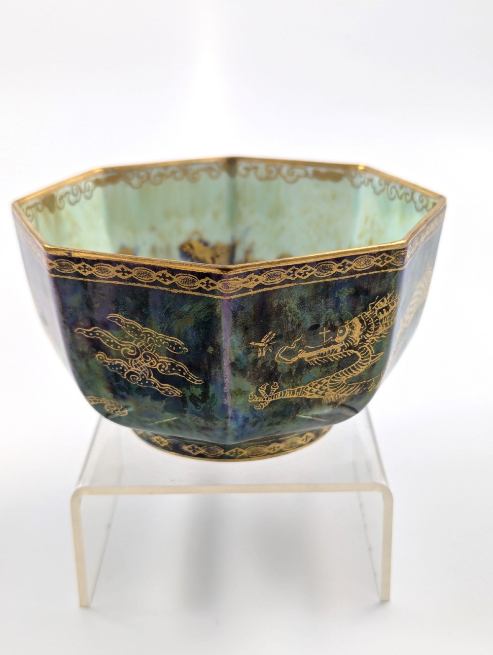 An octagonal blue iridescent porcelain bowl featuring gilded dragon motifs and geometric gold trim around the rim. View III