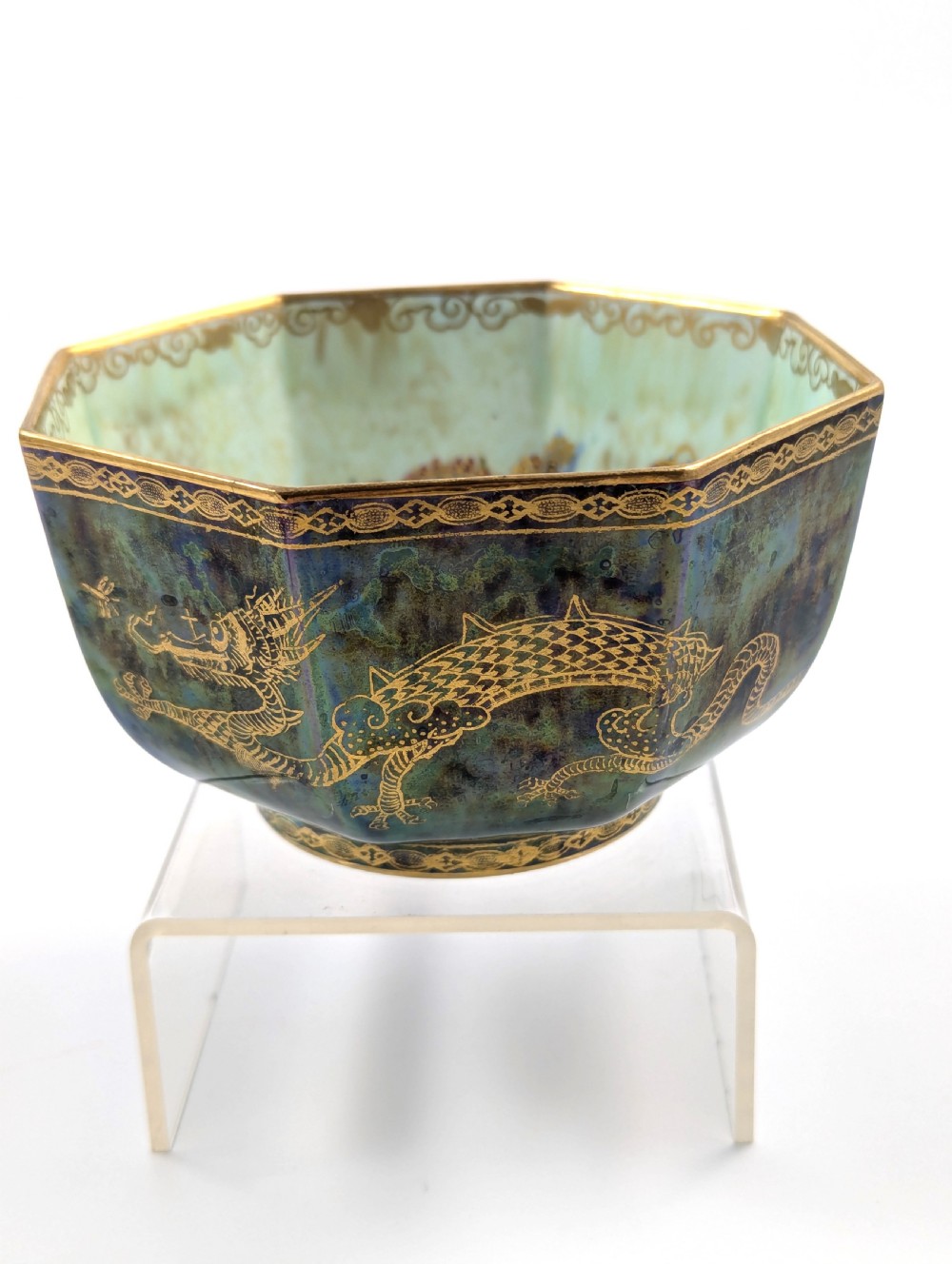 An octagonal blue iridescent porcelain bowl featuring gilded dragon motifs and geometric gold trim around the rim. View IV
