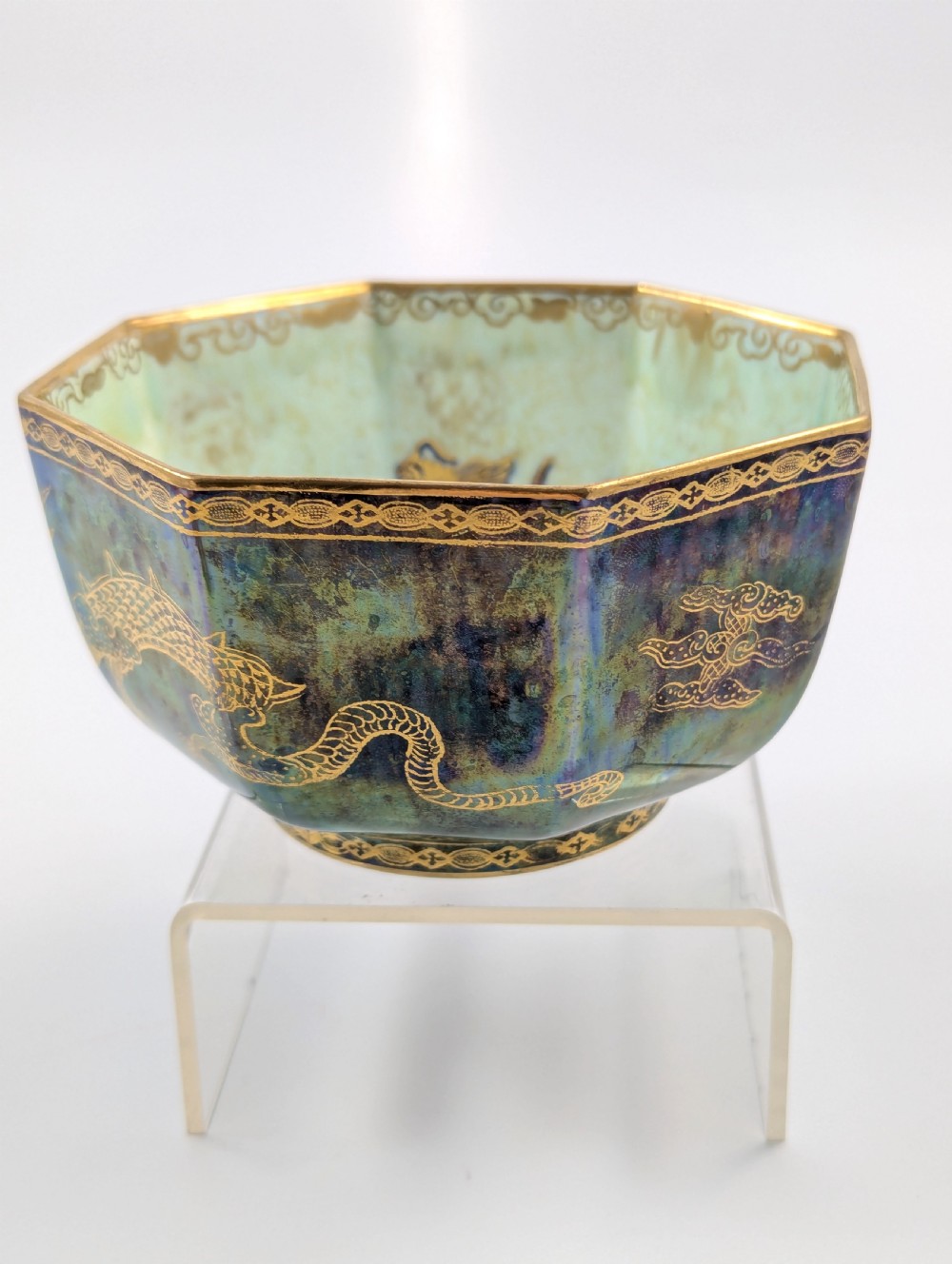 An octagonal blue iridescent porcelain bowl featuring gilded dragon motifs and geometric gold trim around the rim. View V