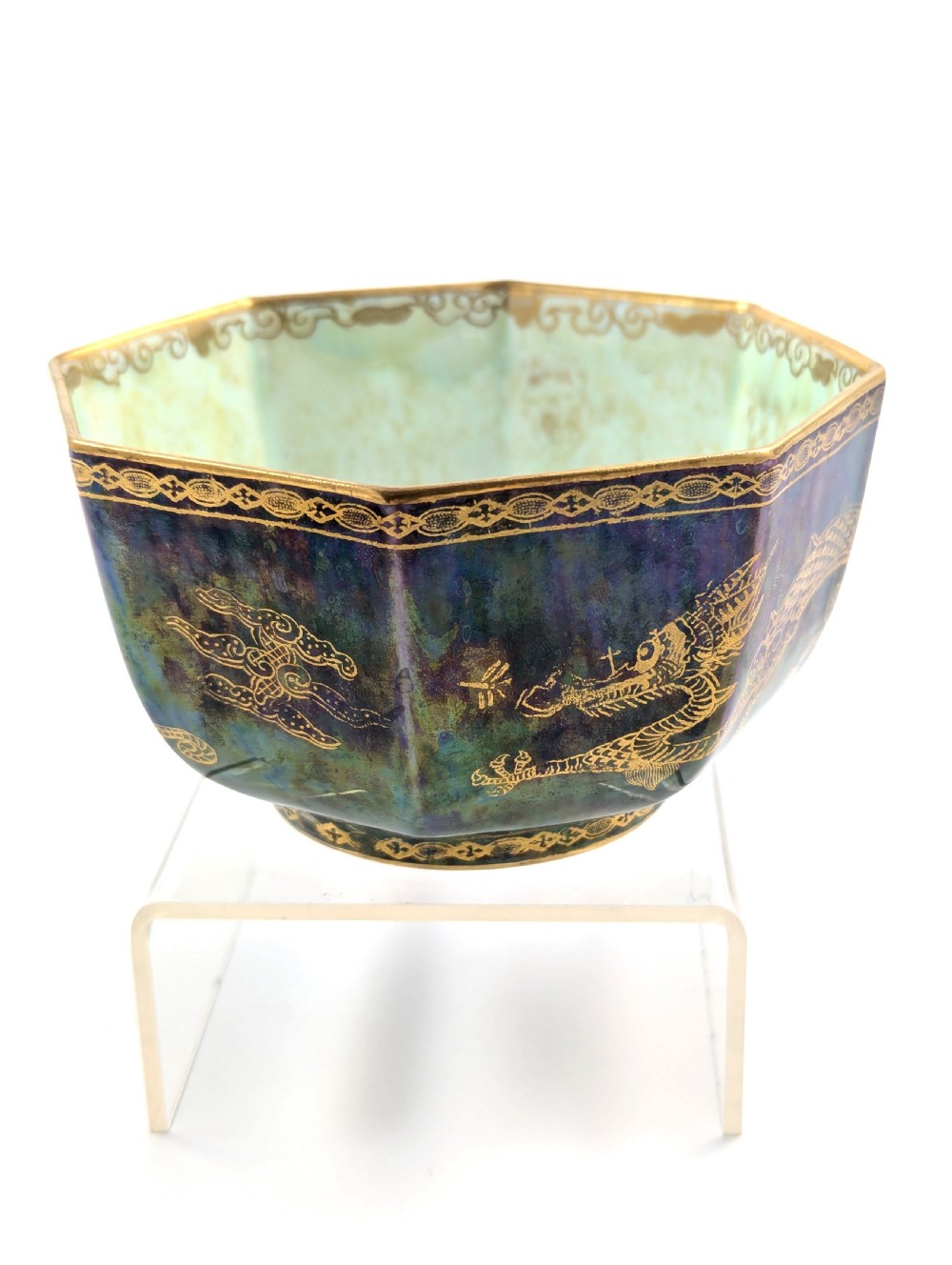 An octagonal blue iridescent porcelain bowl featuring gilded dragon motifs and geometric gold trim around the rim. View VI