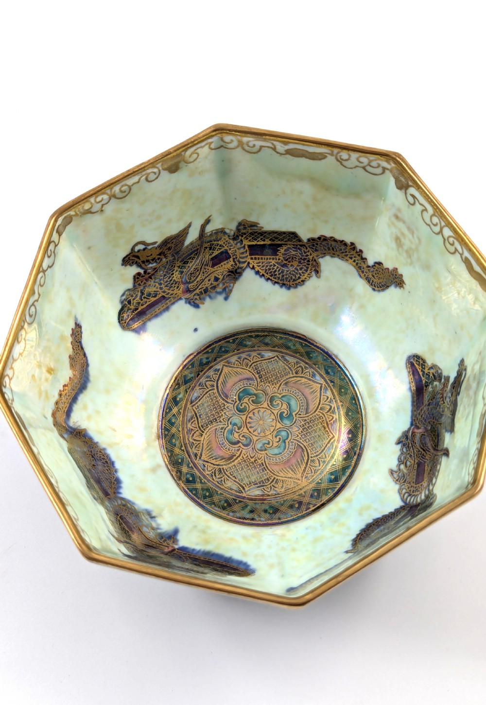 An octagonal blue iridescent porcelain bowl featuring gilded dragon motifs and geometric gold trim around the rim. View VII