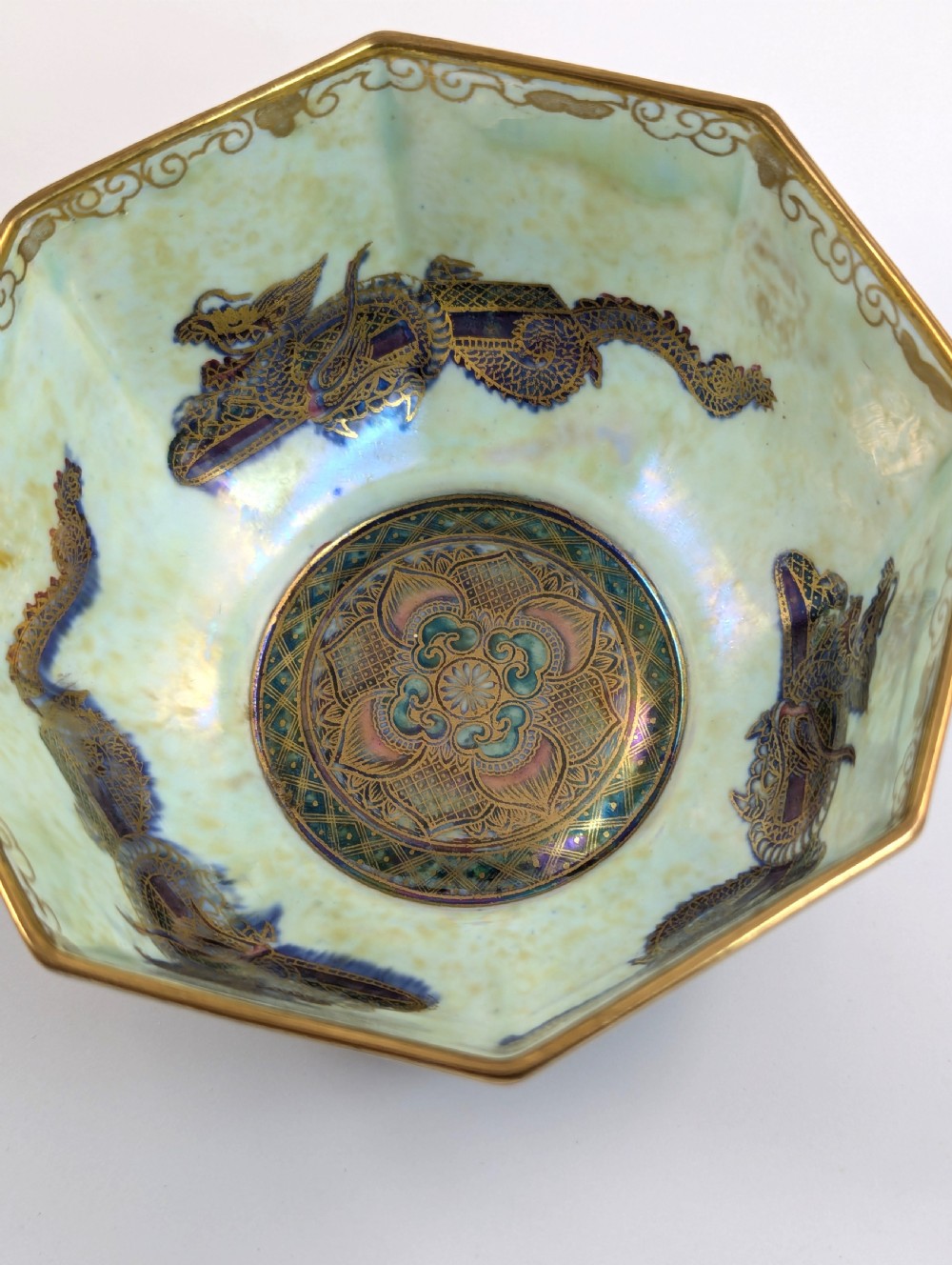 An octagonal blue iridescent porcelain bowl featuring gilded dragon motifs and geometric gold trim around the rim. View VIII
