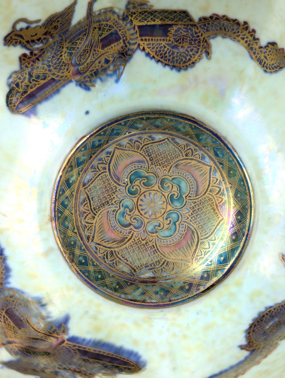 An octagonal blue iridescent porcelain bowl featuring gilded dragon motifs and geometric gold trim around the rim. View IX