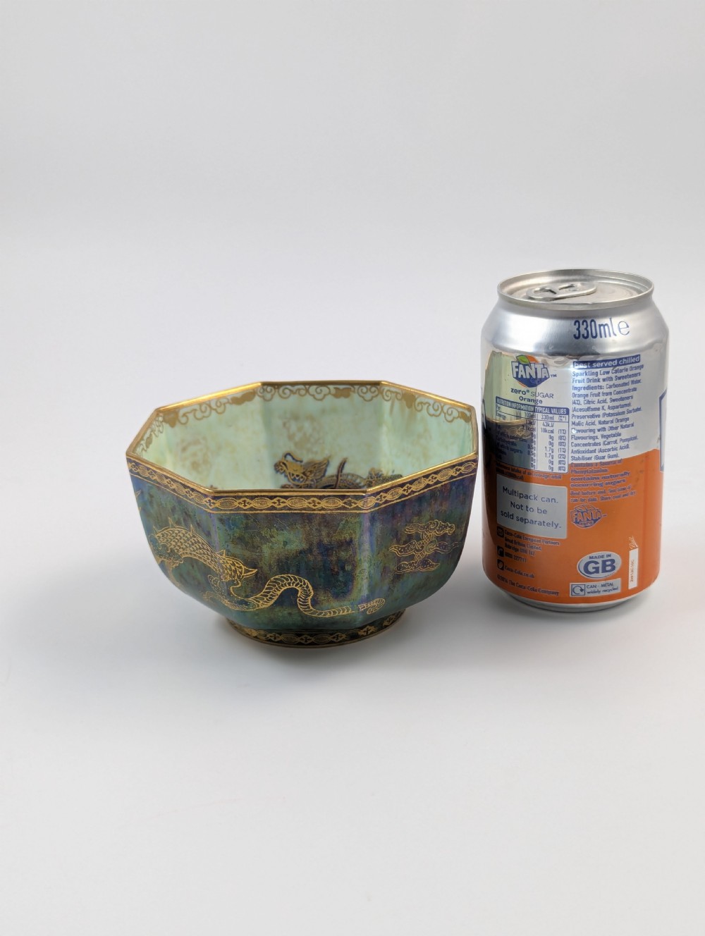 An octagonal blue iridescent porcelain bowl featuring gilded dragon motifs and geometric gold trim around the rim. View XII