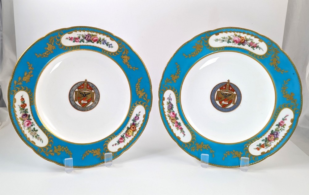 A pair of Victorian Minton porcelain cabinet plates featuring turquoise rims with gilt details, floral cartouches, and a central painted coat of arms.