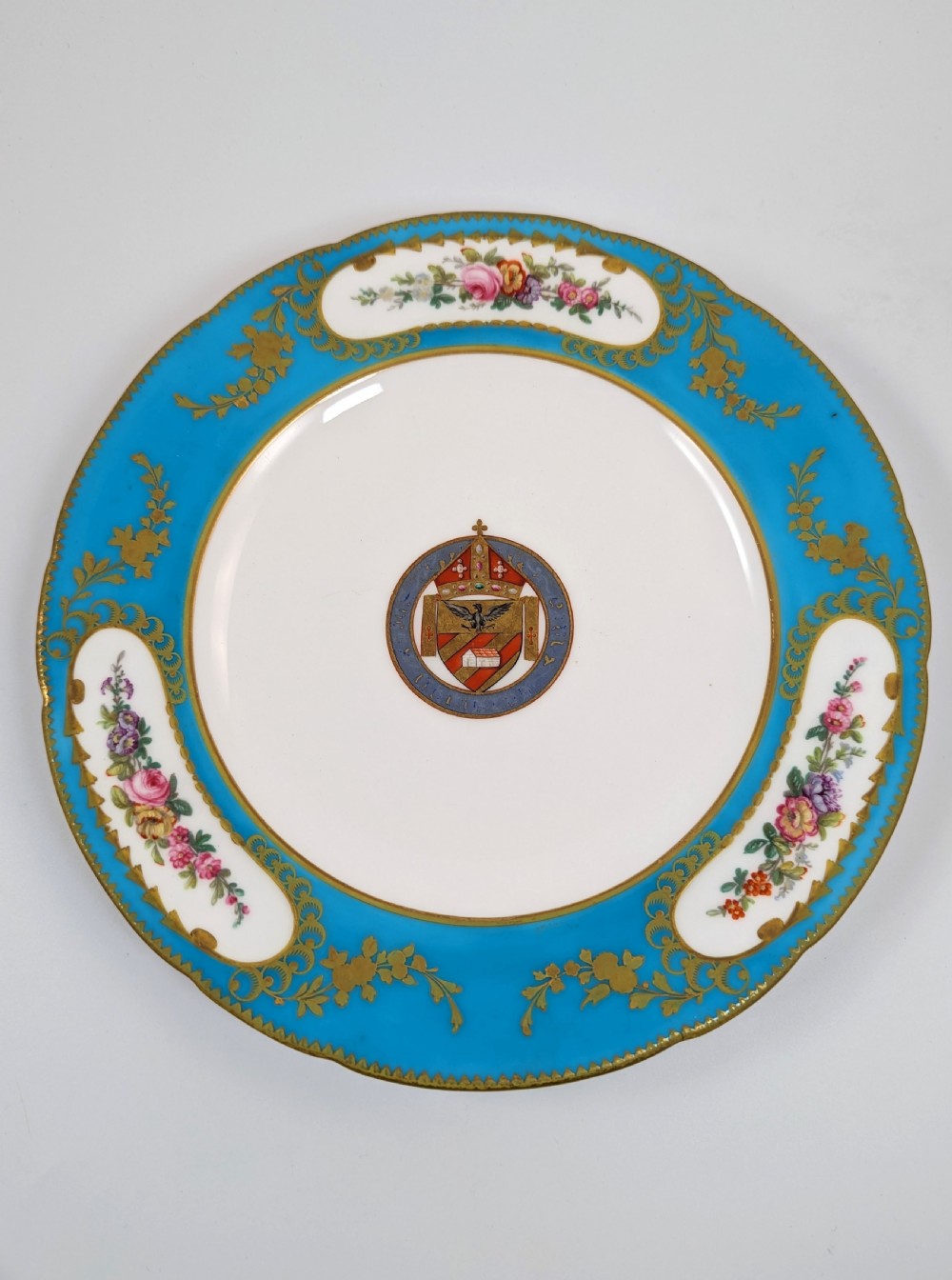 A pair of Victorian Minton porcelain cabinet plates featuring turquoise rims with gilt details, floral cartouches, and a central painted coat of arms. View XI