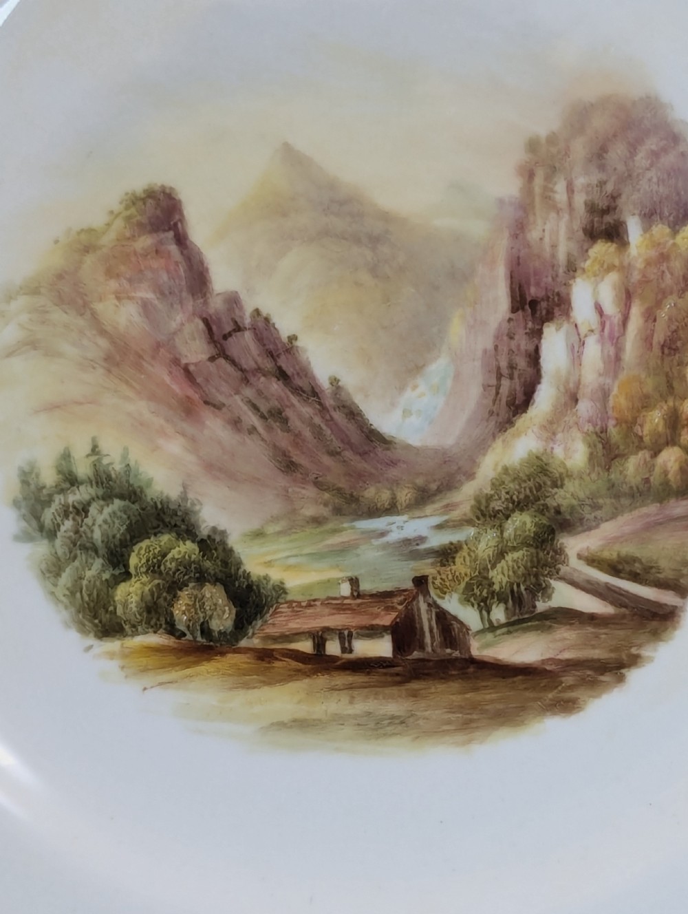 A circular Victorian porcelain cabinet plate featuring a hand-painted landscape scene encircled by a turquoise border with gilded tooling. View II