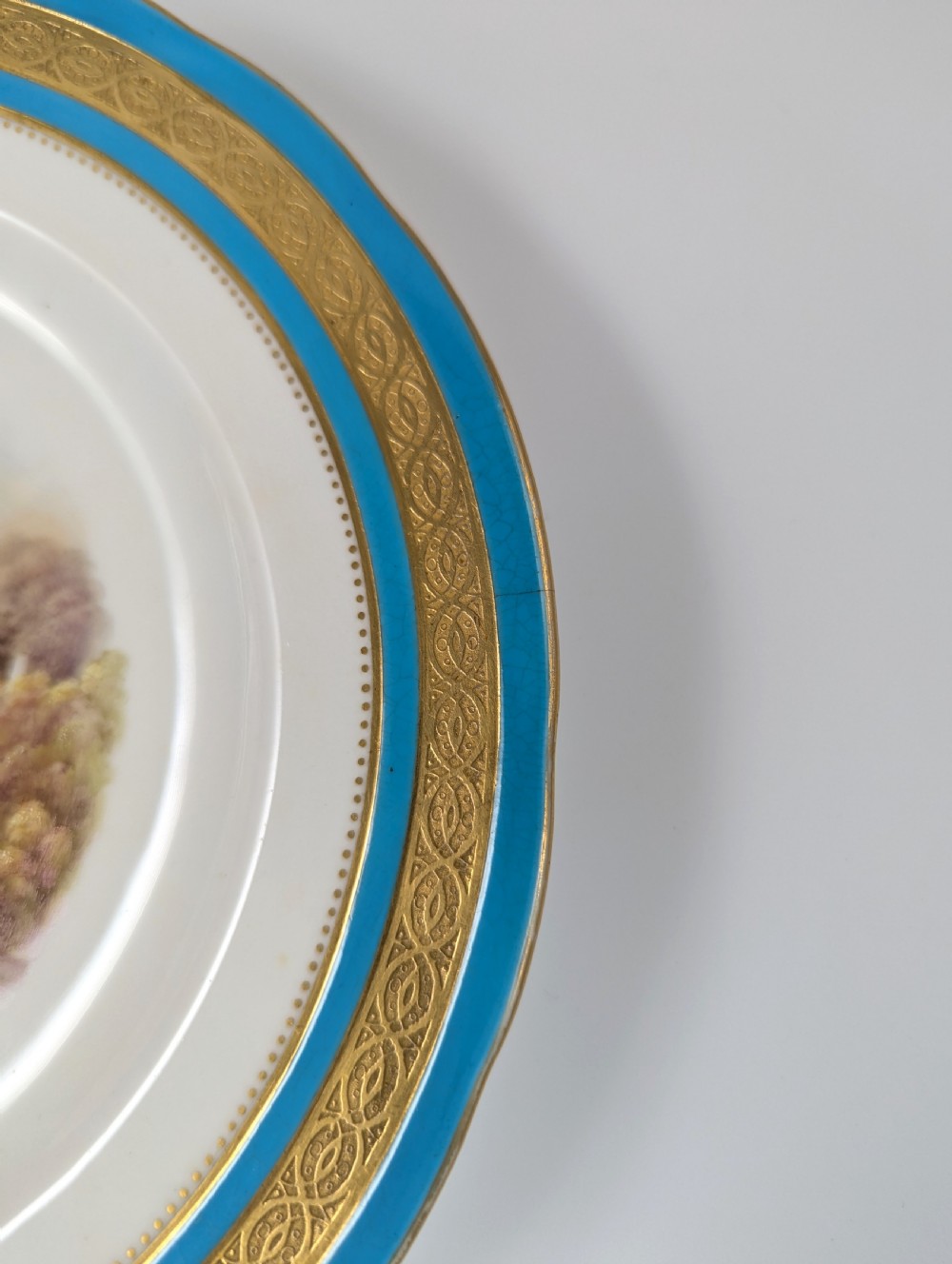 A circular Victorian porcelain cabinet plate featuring a hand-painted landscape scene encircled by a turquoise border with gilded tooling. View VII