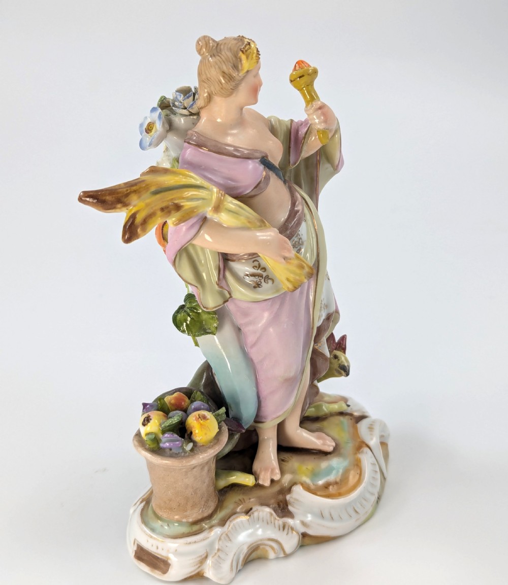 Late 19th-century German Volkstedt porcelain allegorical figurine depicting a draped female figure holding a torch and sheaf of wheat atop a gilded scroll base. View V