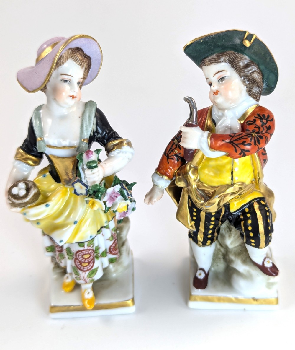 A pair of early 19th-century Chelsea-style hand-painted porcelain figurines depicting a female gardener and a male farmer with gilded accents.