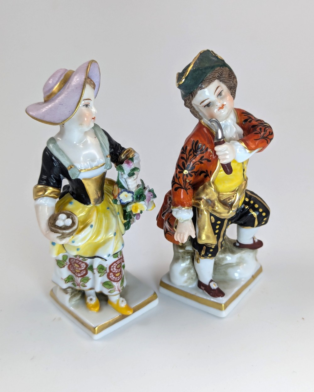 A pair of early 19th-century Chelsea-style hand-painted porcelain figurines depicting a female gardener and a male farmer with gilded accents. View V