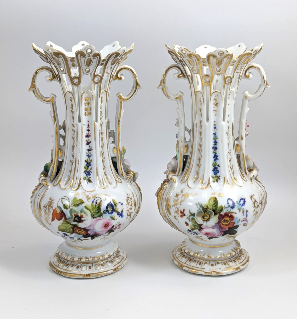 A pair of nineteenth-century white hard-paste porcelain vases featuring reticulated necks, gilded scroll handles, painted botanical panels, and applied ceramic flowers. View III