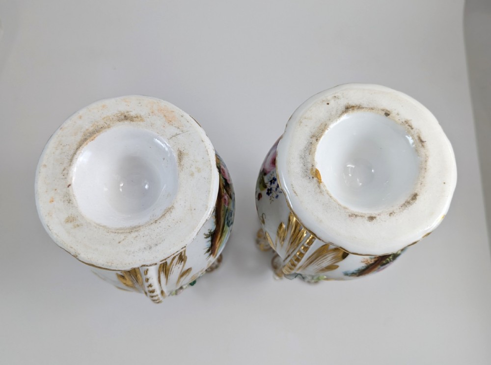 A pair of nineteenth-century white hard-paste porcelain vases featuring reticulated necks, gilded scroll handles, painted botanical panels, and applied ceramic flowers. View V
