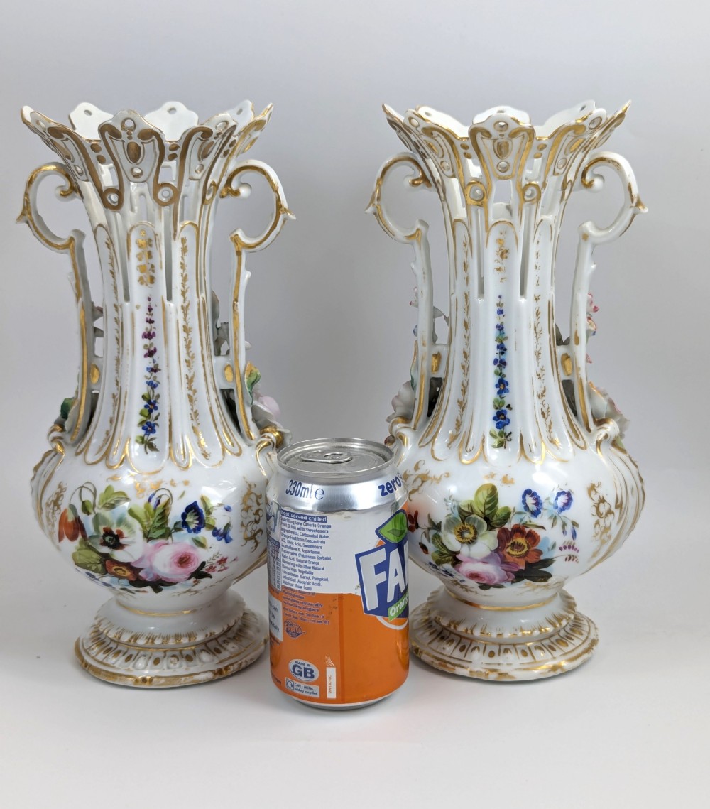 A pair of nineteenth-century white hard-paste porcelain vases featuring reticulated necks, gilded scroll handles, painted botanical panels, and applied ceramic flowers. View XI