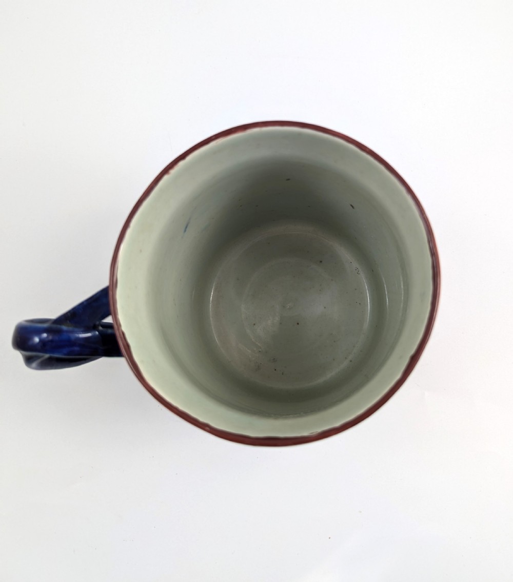 A cylindrical antique Chinese Kangxi porcelain tankard decorated with hand-painted pagodas, palm trees, and an iron-red scale pattern border. View VIII