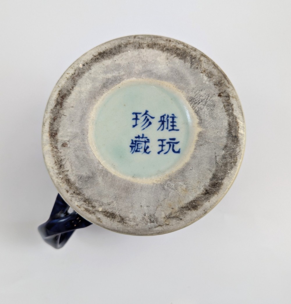 A cylindrical antique Chinese Kangxi porcelain tankard decorated with hand-painted pagodas, palm trees, and an iron-red scale pattern border. View IX